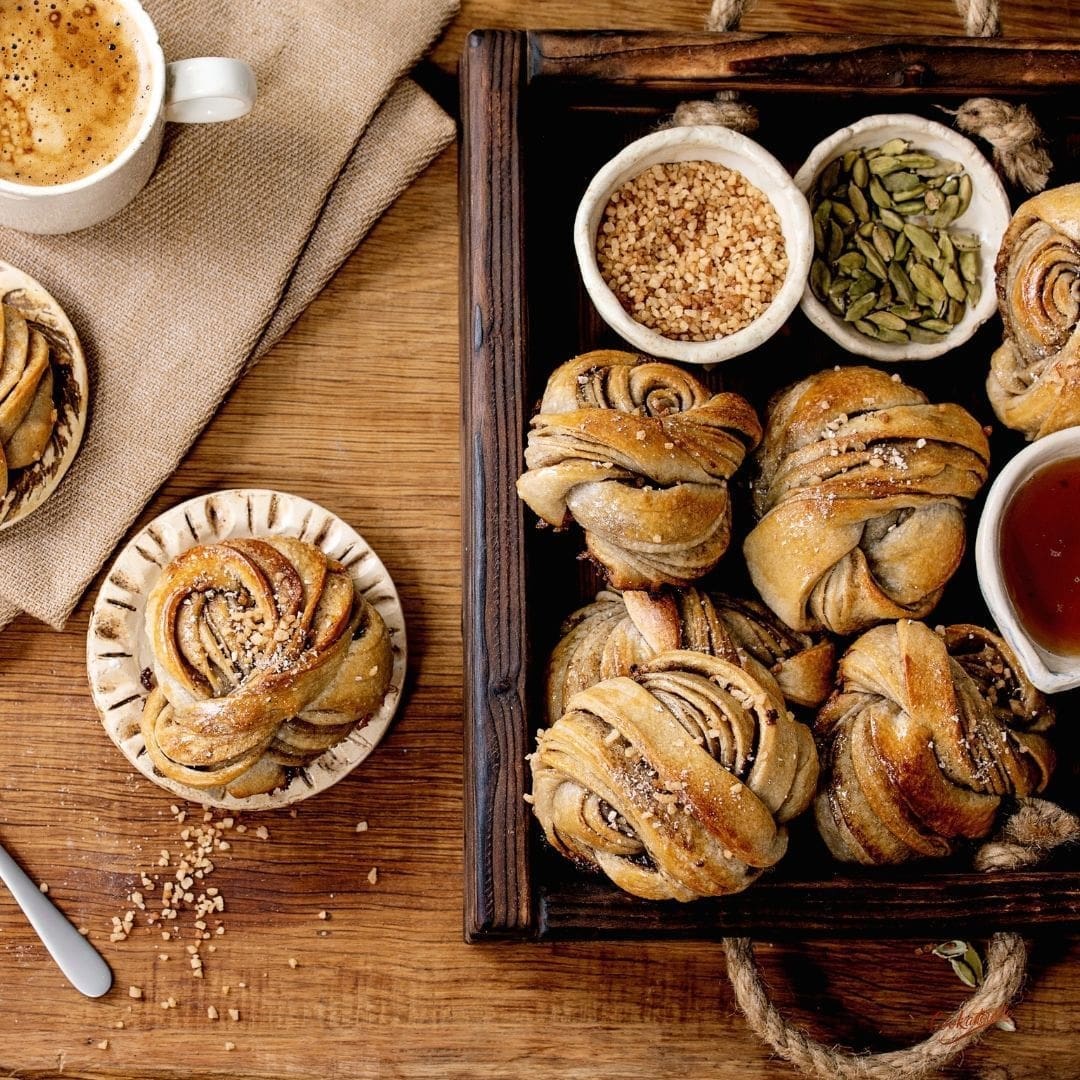 Freshly baked Swedish Cardamom Buns (Kardemummabullar), beautifully twisted and sprinkled with pearl sugar.